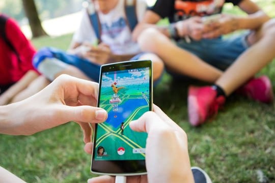 Jugendliche spielen in einem Park in Stuttgart auf ihren Smartphones.