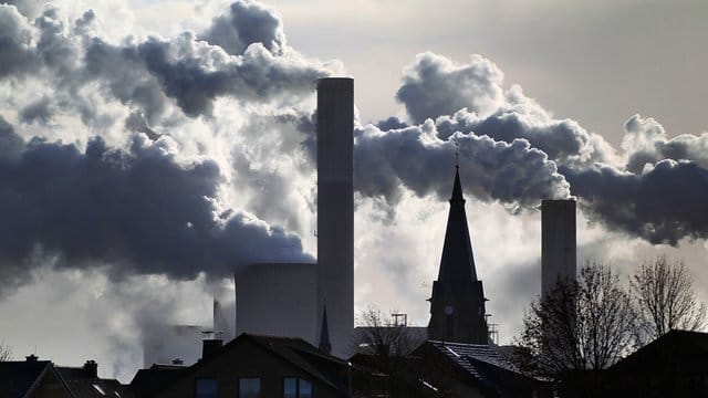 Rauch und Dampf steigen aus den Kühltürmen und Schornsteinen des Braunkohlekraftwerks Frimmersdorf bei Grevenbroich.