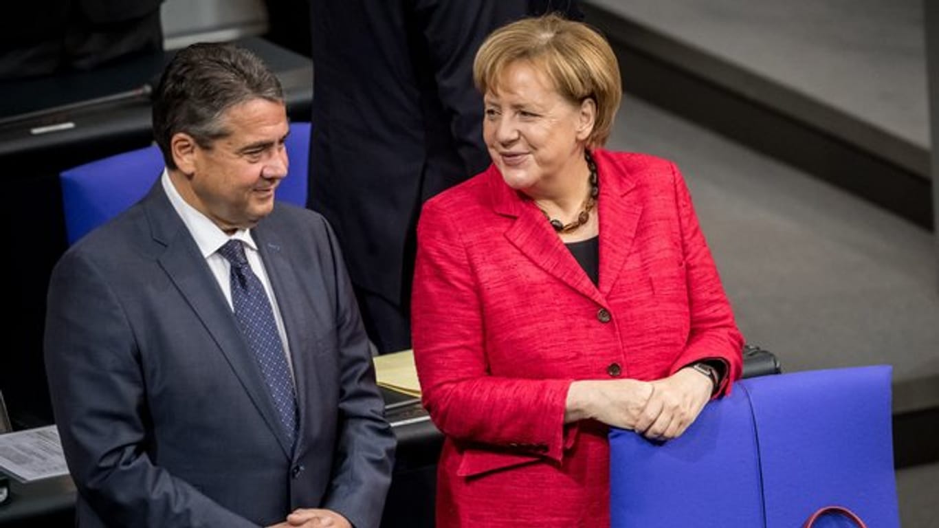Bundeskanzlerin Angela Merkel und Außenminister Sigmar Gabriel unterhalten sich im Bundestag in Berlin.