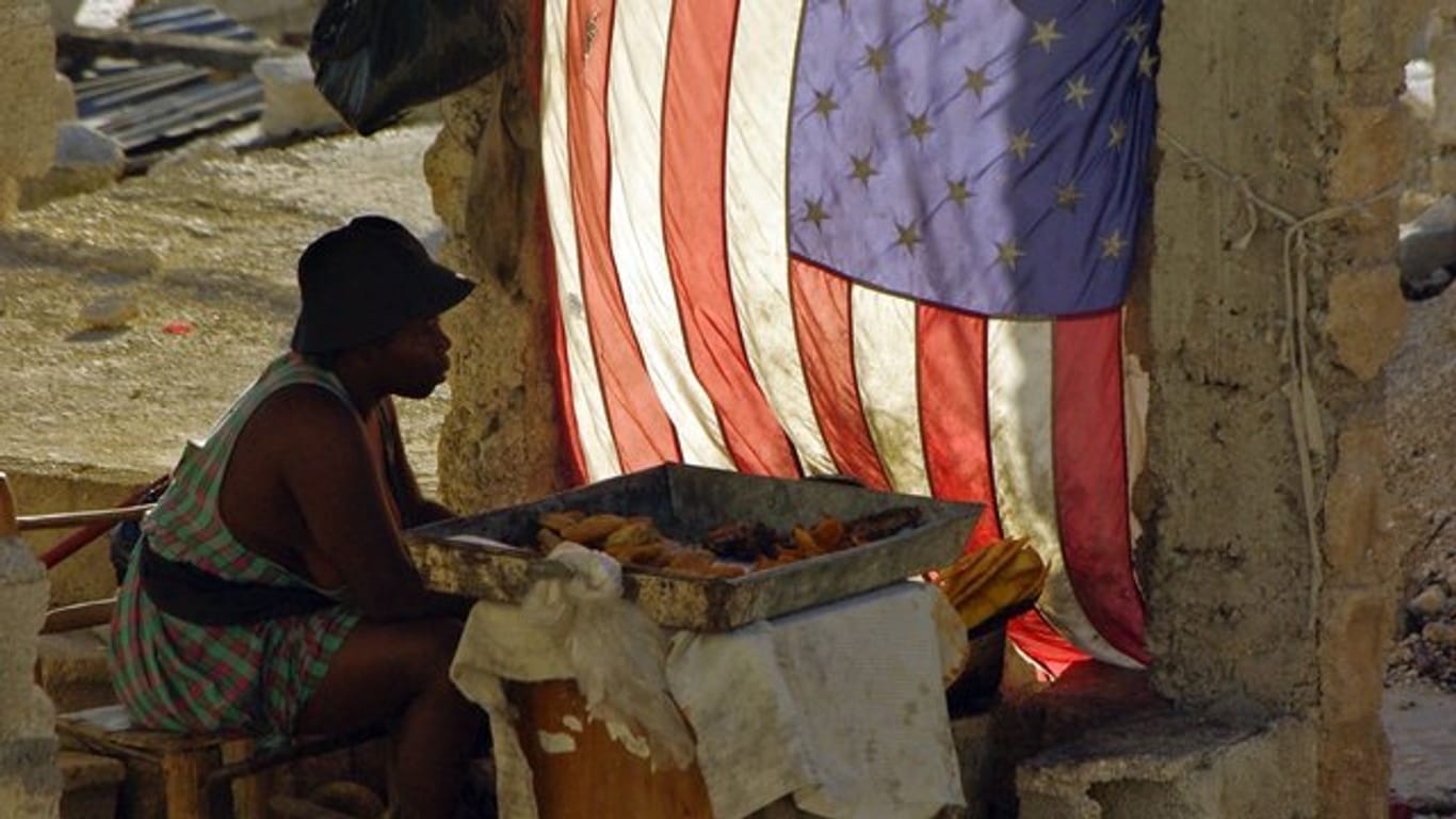 Neben einer US-Flagge sitzend verkauft eine Frau in Port-au-Prince gebackene Bananen.