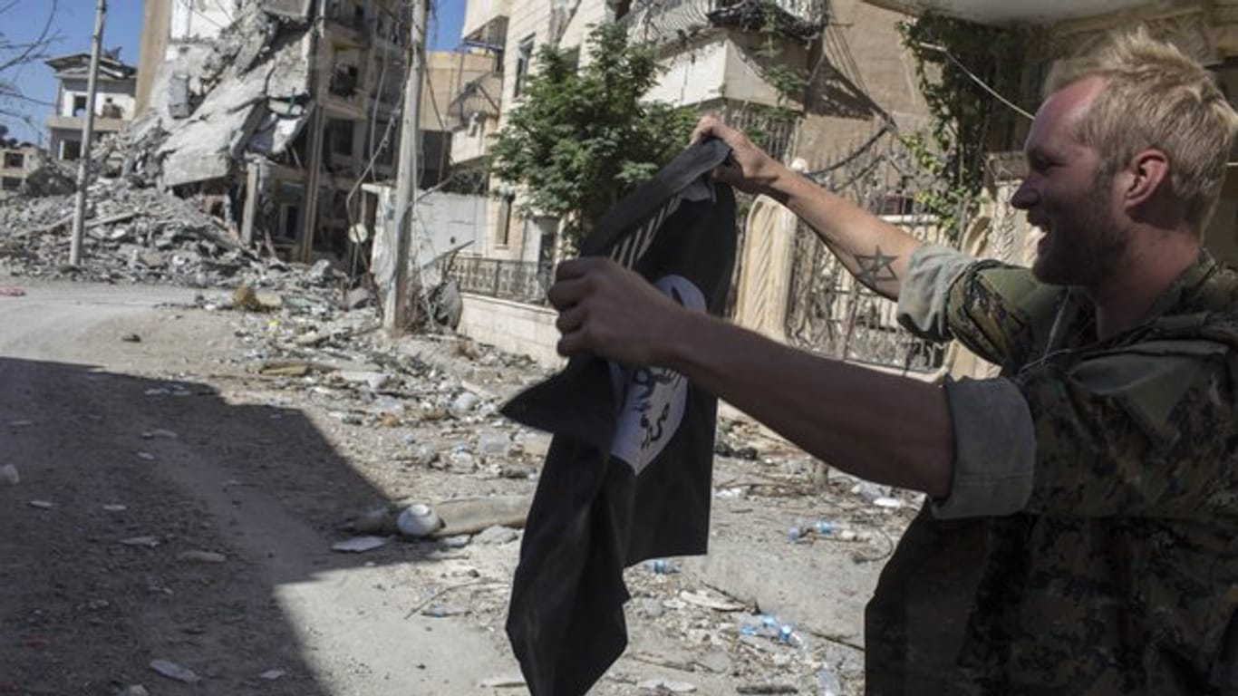 Ein Soldat hält Mitte Oktober in der Stadt Al-Rakka in Syrien eine zurückgelassene Flagge der Terrormiliz in den Händen.