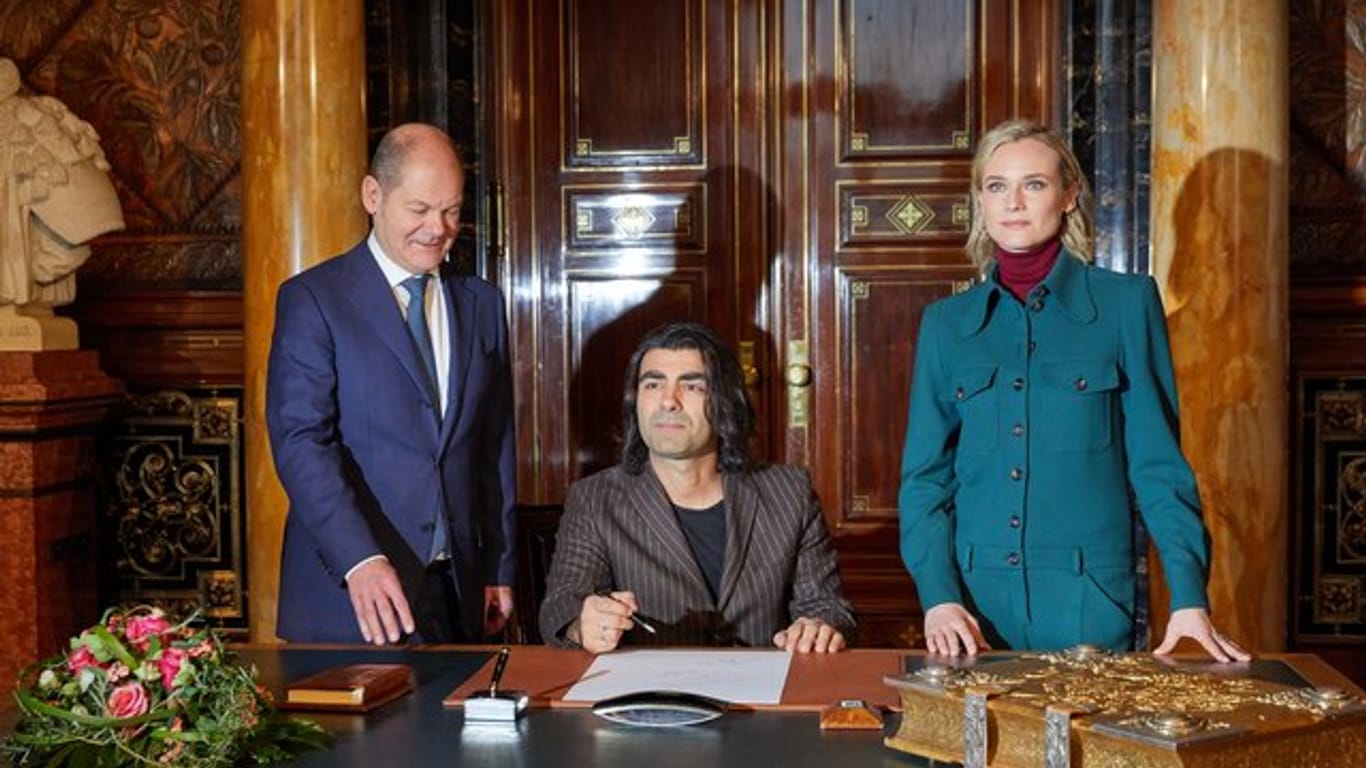 Fatih Akin (sitzend) und Diane Kruger schreiben sich im Hamburger Rathaus beim Ersten Bügermeister Olaf Scholz (SPD) in das Goldene Buch der Stadt ein.