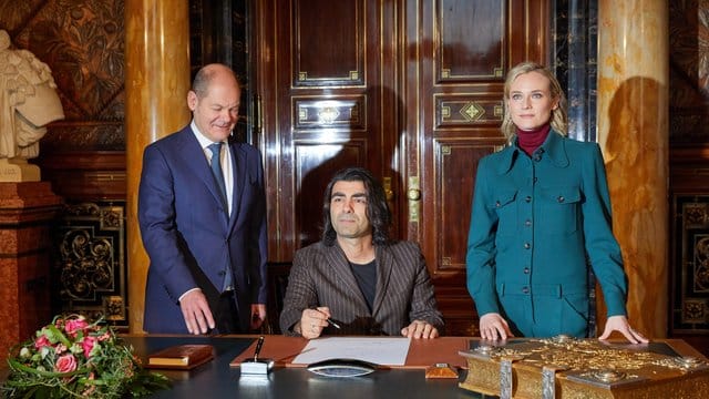 Fatih Akin (sitzend) und Diane Kruger schreiben sich im Hamburger Rathaus beim Ersten Bügermeister Olaf Scholz (SPD) in das Goldene Buch der Stadt ein.