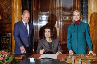 Fatih Akin (sitzend) und Diane Kruger schreiben sich im Hamburger Rathaus beim Ersten Bügermeister Olaf Scholz (SPD) in das Goldene Buch der Stadt ein.