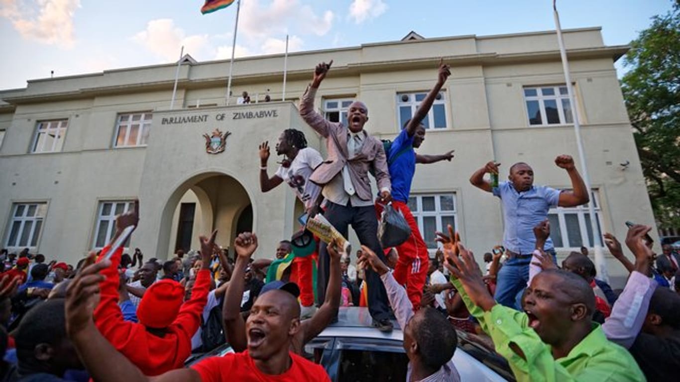 Menschen feiern vor dem Parlamentsgebäude in Harare den Rücktritt von Robert Mugabe.