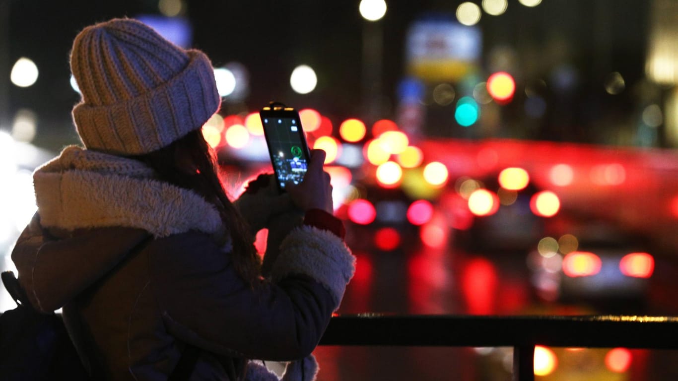 Eine junge Frau macht ein Foto mit ihrem Smartphone.
