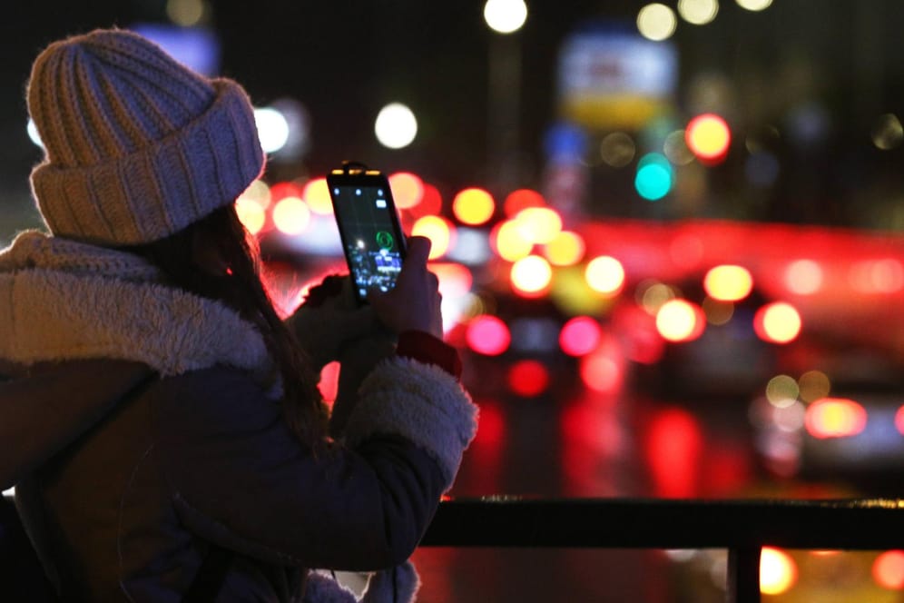 Eine junge Frau macht ein Foto mit ihrem Smartphone.
