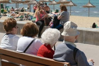 Senioren sitzen auf einer Bank an der Playa de Palma in S'Arenal bei Palma de Mallorca.