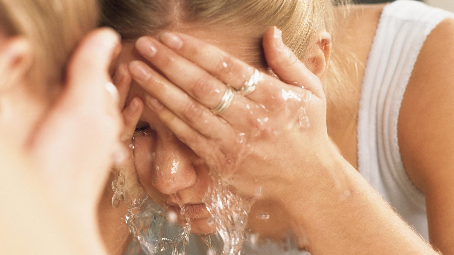 Frau wäscht Gesicht mit Wasser