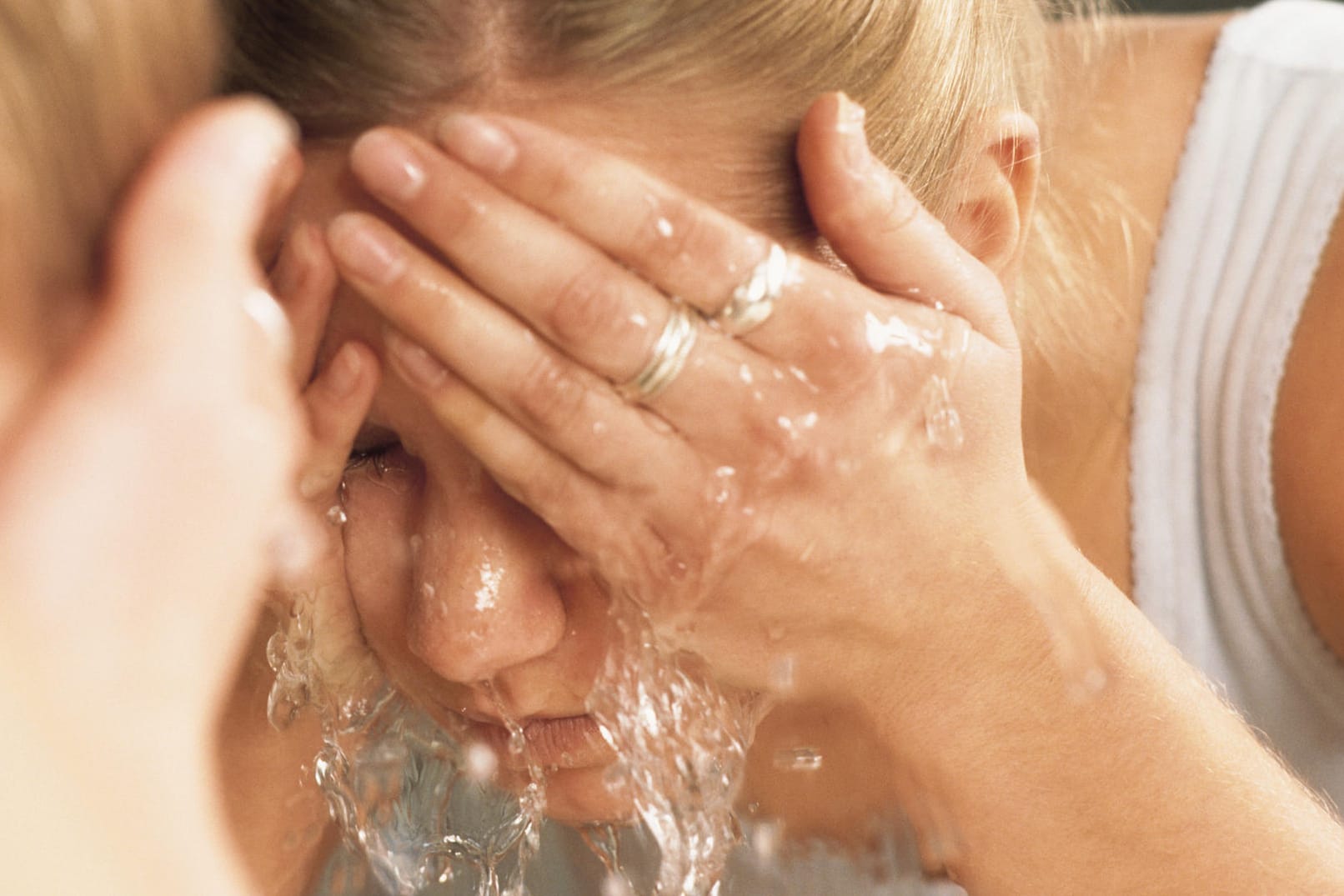 Frau wäscht Gesicht mit Wasser