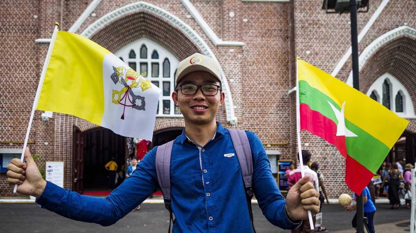 Ein Einwohner aus Myanmar hält die Vatikan und die Myanmar-Flagge.