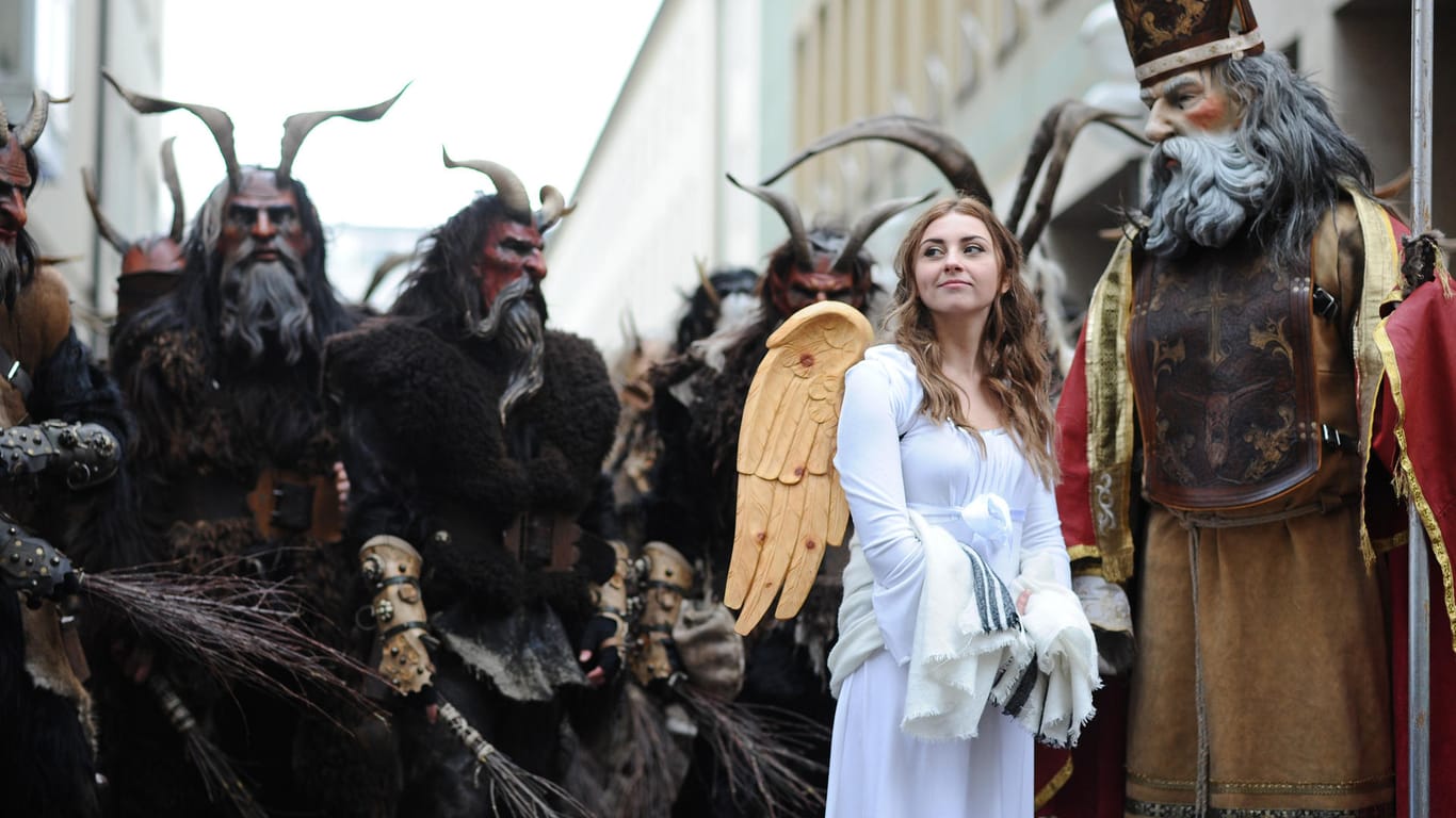 Weihnachtsmarkt München: Ein Engel, der Heilige Nikolaus und mehrere Krampusse vor dem traditionellen Krampuslauf über den Christkindlmarkt.