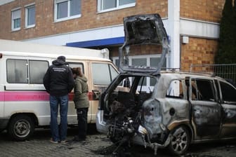 Kriminaltechniker begutachten in Bergkamen ein Auto vor einem Haus, in dem es in der Nacht gebrannt hat.