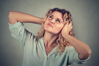 annoyed stressed woman covering ears with hands looking up