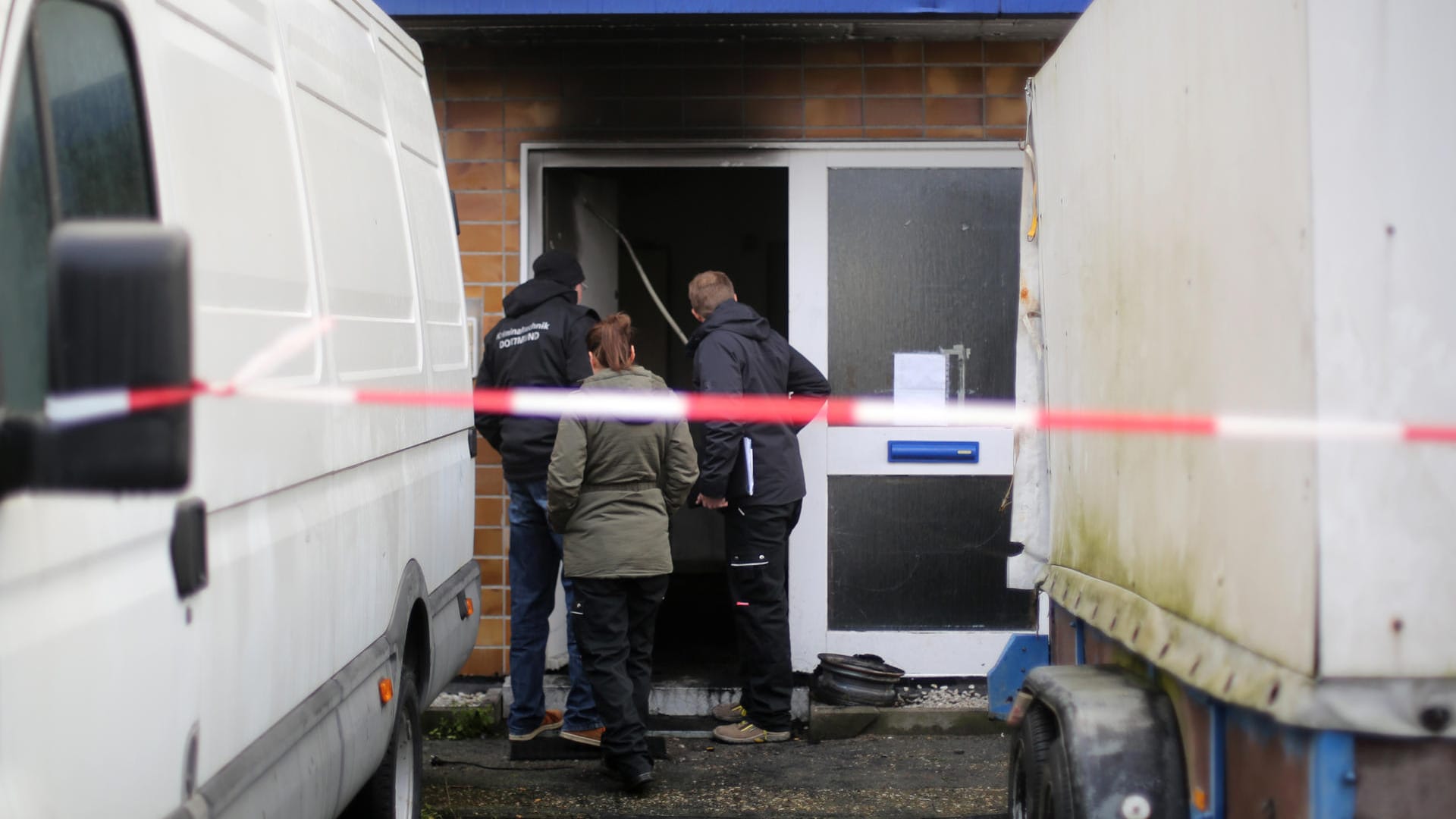 Kriminaltechniker begutachten den Eingang zu einem Haus nach einem Brand