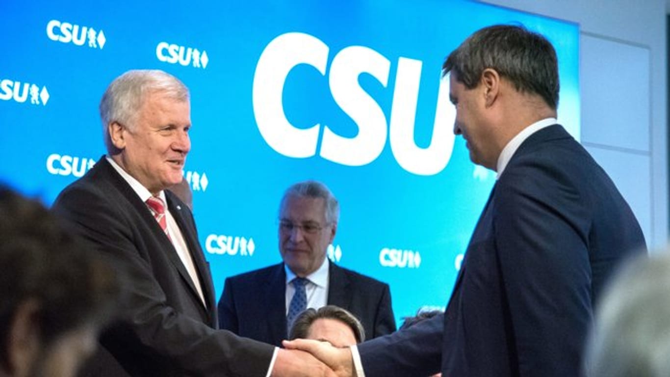 Der bayerische Ministerpräsident Horst Seehofer und sein designierter Nachfolger Markus Söder (r) geben sich die Hand.