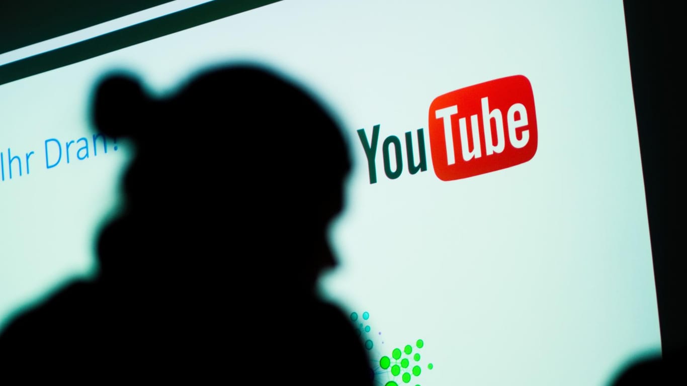 Die Silhouette eines Menschen ist vor einem Bildschirm mit dem YouTube-Logo zu sehen.