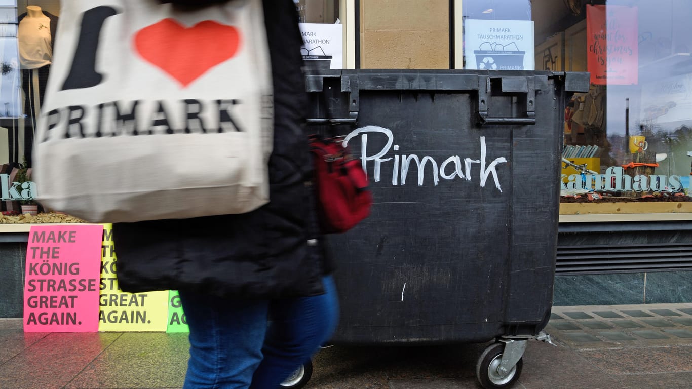 Eine Frau mit einer "I love Primark"-Tasche läuft an einem Container vorbei, der als Kritik an der Eröffnung einer weiteren Primark-Filiale in Stuttgart aufgestellt wurde.