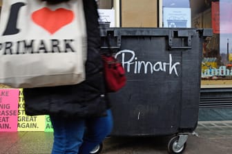 Eine Frau mit einer "I love Primark"-Tasche läuft an einem Container vorbei, der als Kritik an der Eröffnung einer weiteren Primark-Filiale in Stuttgart aufgestellt wurde.