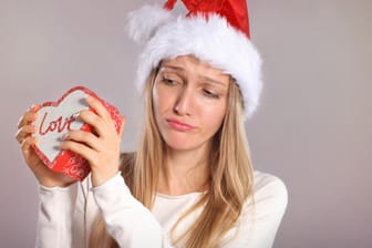 Disappointed woman with a Santa hat holding a gift box