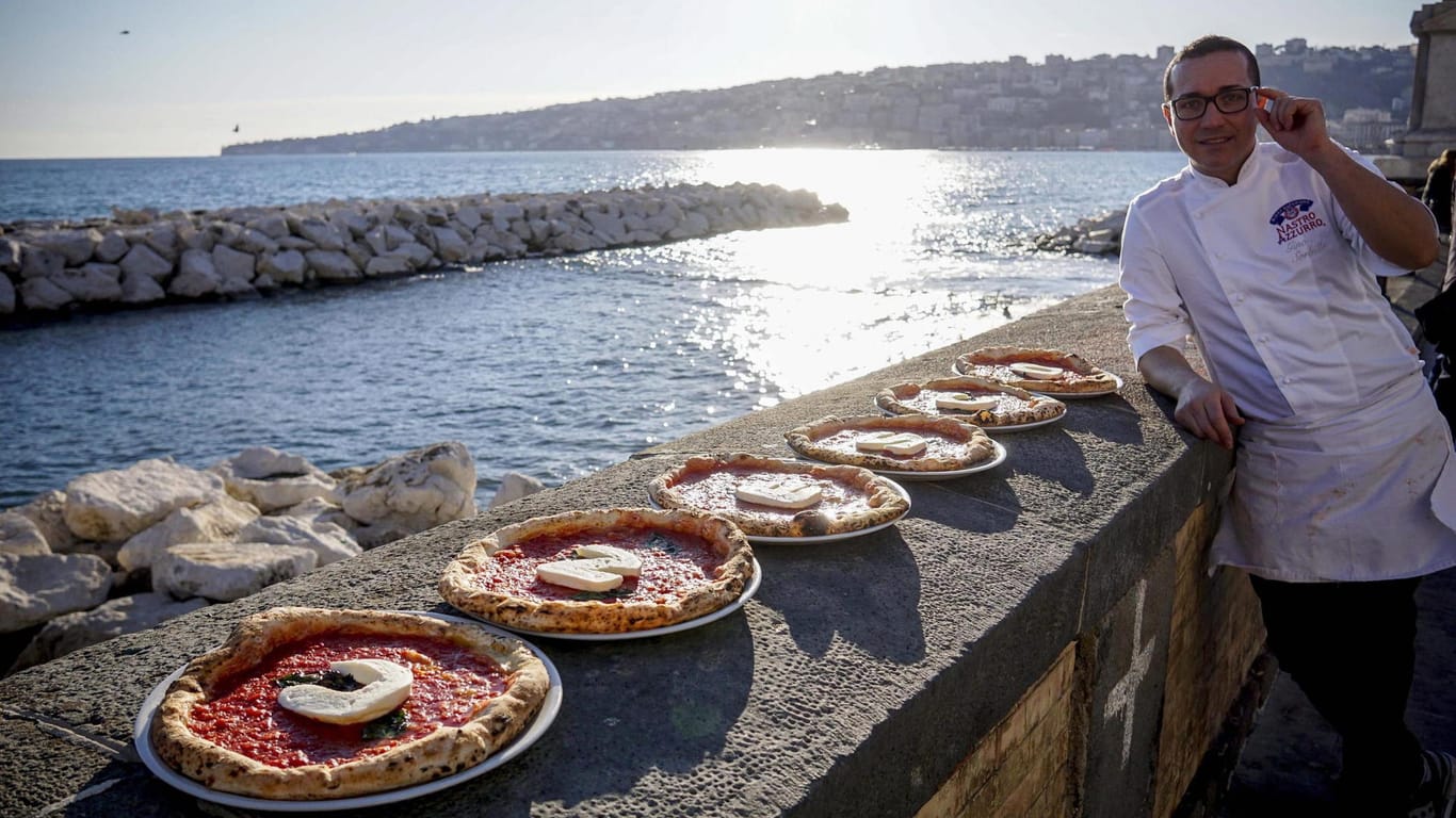 Der italienische Küchenchef Gino Sorbillo posiert in Neapel mit Pizzen, deren Auflage das Wort 'Unesco' bildet. Das war noch die Bewerbungsphase - jetzt ist die Kunst der neapolitanischen Pizzabäcker immaterielles Kulturerbe.