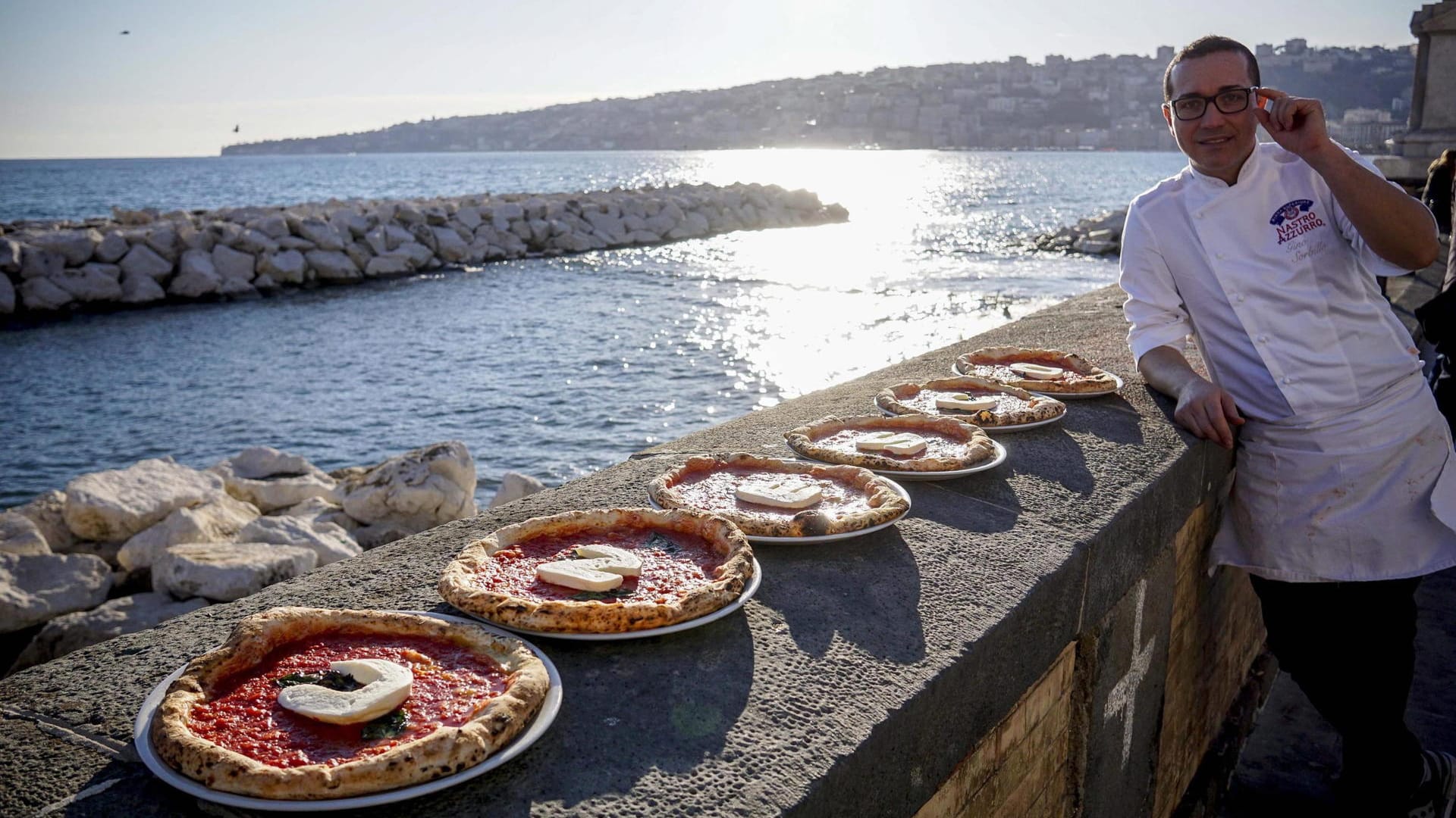 Der italienische Küchenchef Gino Sorbillo posiert in Neapel mit Pizzen, deren Auflage das Wort 'Unesco' bildet. Das war noch die Bewerbungsphase - jetzt ist die Kunst der neapolitanischen Pizzabäcker immaterielles Kulturerbe.