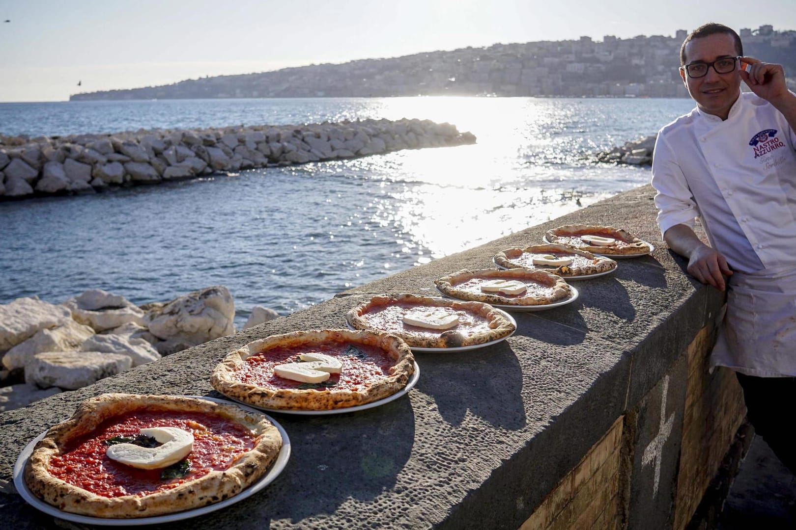 Der italienische Küchenchef Gino Sorbillo posiert in Neapel mit Pizzen, deren Auflage das Wort 'Unesco' bildet. Das war noch die Bewerbungsphase - jetzt ist die Kunst der neapolitanischen Pizzabäcker immaterielles Kulturerbe.