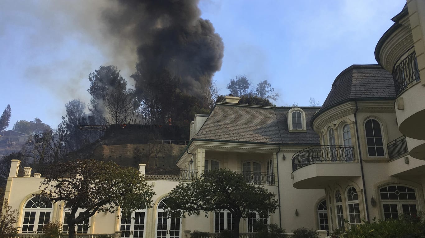 Das Buschfeuer frisst sich in der Nähe einer Villa einen Abhang hinunter.