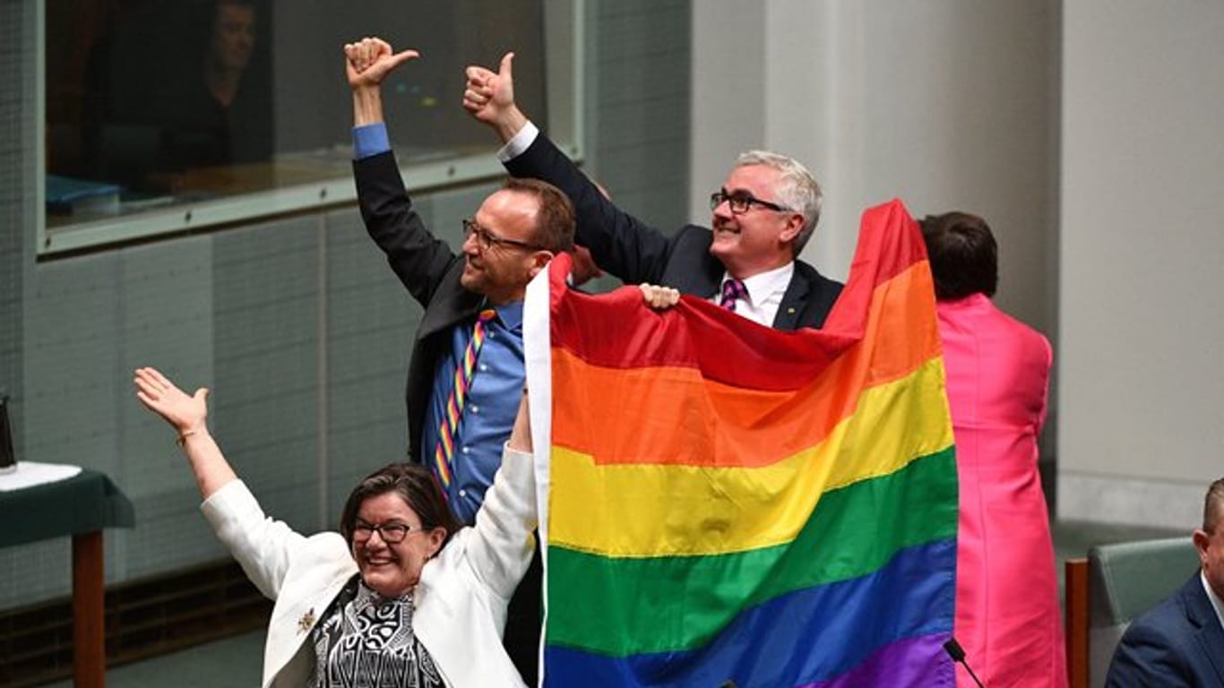 Die Parlamentsmitglieder Cathy McGowan, Adam Brandt und Andrew Wilkie präsentieren in Canberra eine Regenbogenfahne.