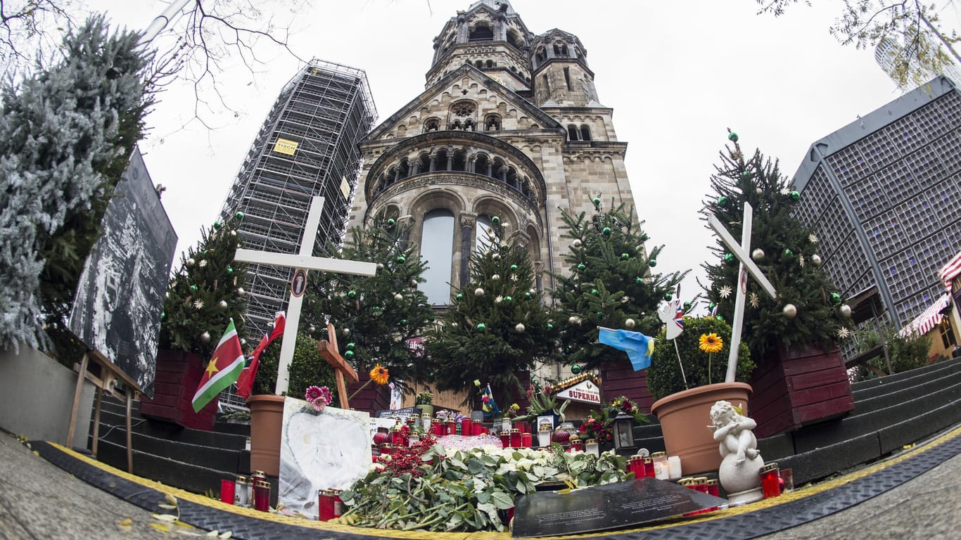 Ein Jahr nach dem Terroranschlag: Passanten stellen Blumen und Kerzen auf dem Breitscheidplatz an der provisorischen Gedenkstätte für die Opfer auf.