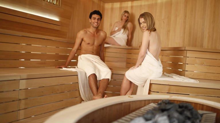 Entspannender Saunabesuch von zwei Frauen und einem Mann.