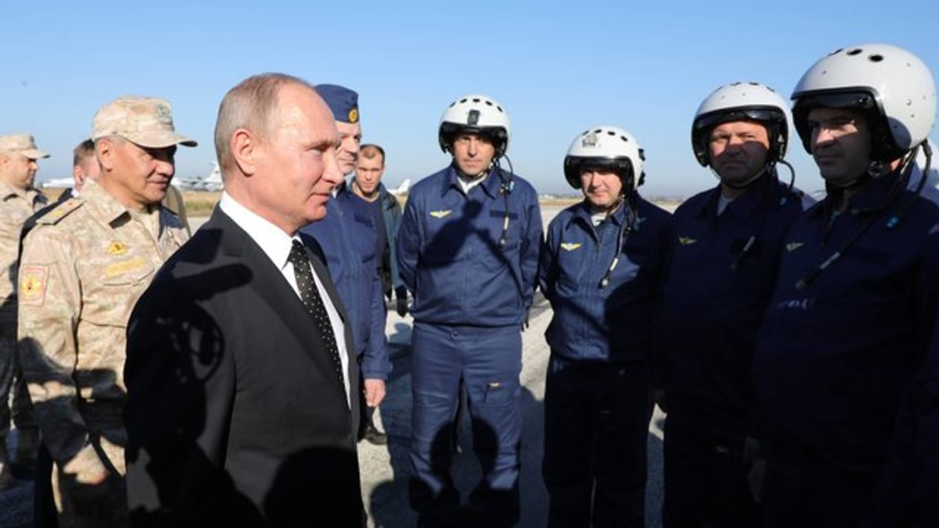 Wladimir Putin und Verteidigungsminister Sergej Schoigu (l) unterhalten sich mit russischen Militärpiloten auf der russischen Luftwaffenbasis Hamaimim in der Provinz Latakia in Syrien.