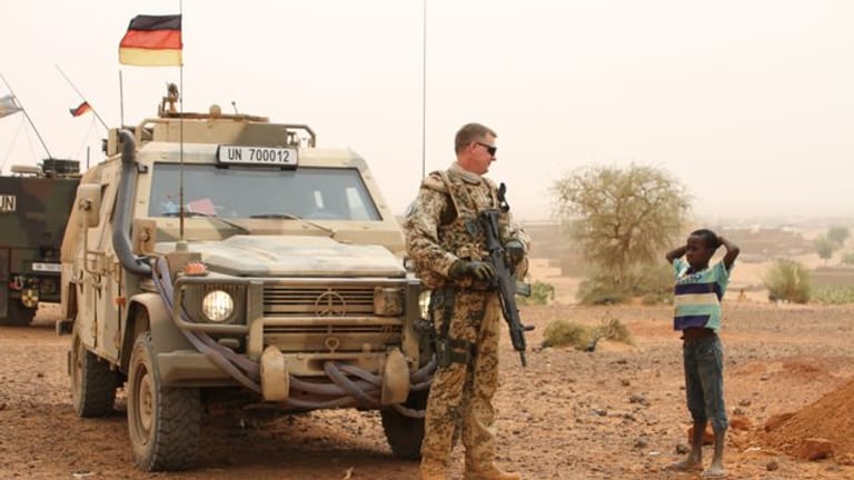 Ein deutscher Blauhelmsoldat unterhält sich während einer Patrouille in der Stadt Gao im Norden Malis mit einem Kind.