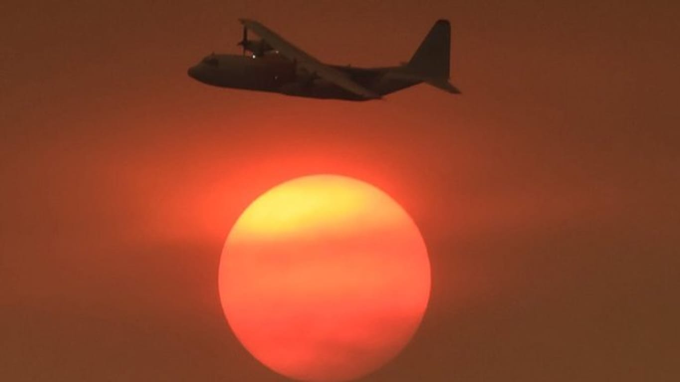 Hilfe in Anflug: Vor der von Rauchschwaden verdunkelten Sonne fliegt im kalifornischen Carpinteria ein Löschflugzeug einen Einsatz.
