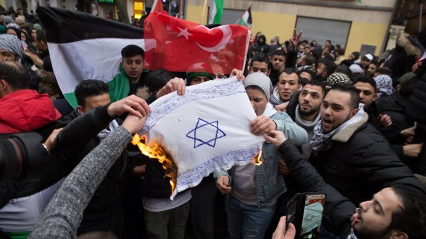 Teilnehmer einer Demonstration verbrennen eine selbstgemalte Fahne mit einem Davidstern im Berliner im Stadtteil Neukölln.