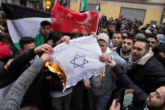 Teilnehmer einer Demonstration verbrennen eine selbstgemalte Fahne mit einem Davidstern im Berliner im Stadtteil Neukölln.