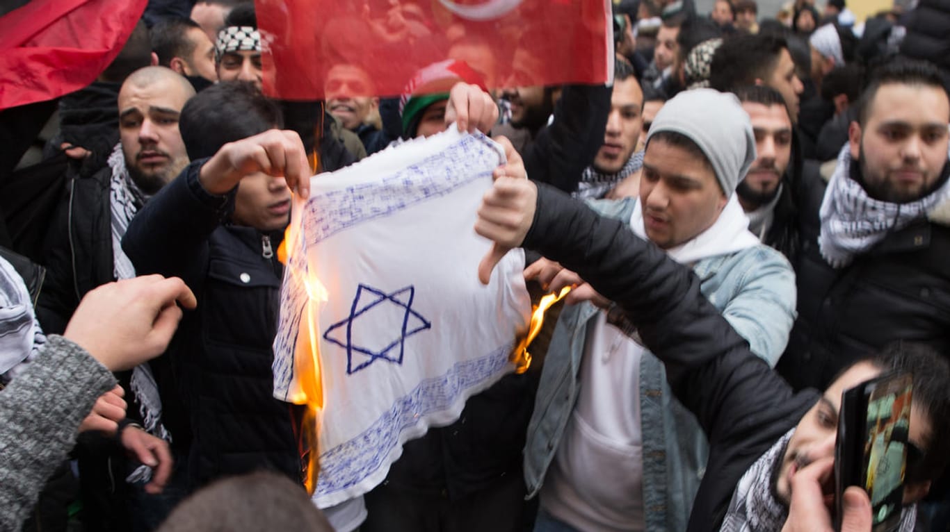 Teilnehmer einer Demonstration verbrennen eine selbstgemalte Fahne mit einem Davidstern in Berlin.