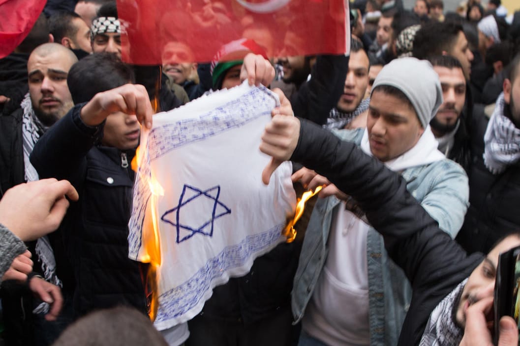 Teilnehmer einer Demonstration verbrennen eine selbstgemalte Fahne mit einem Davidstern in Berlin.