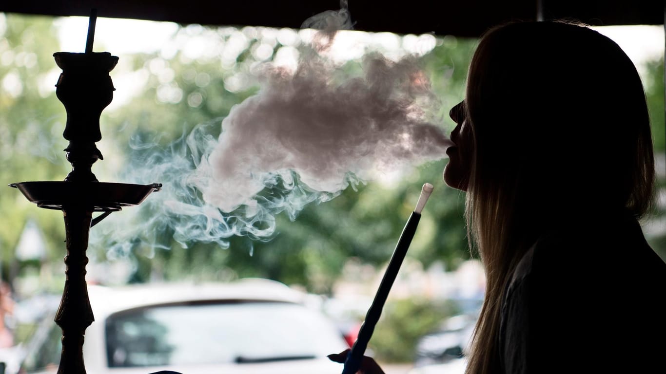 Eine junge Frau raucht eine Shisha-Pfeife.