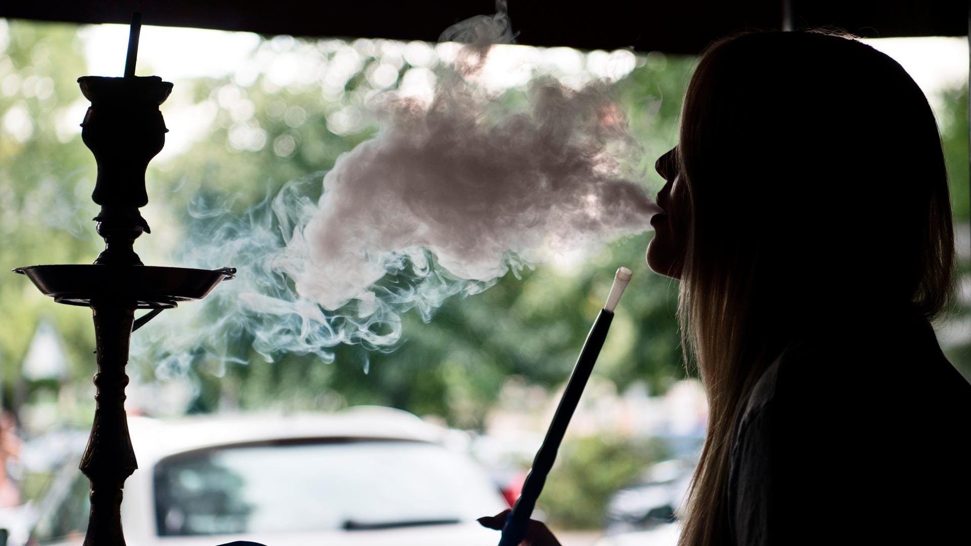 Eine junge Frau raucht eine Shisha-Pfeife. Eine junge Frau raucht eine Shisha-Pfeife.