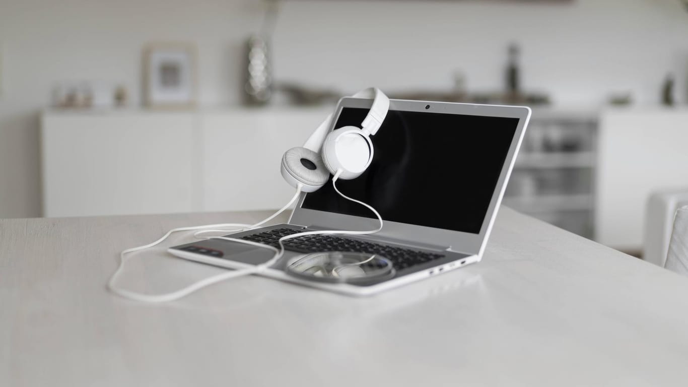 Ein Laptop mit Kopfhörern steht auf einem Tisch.