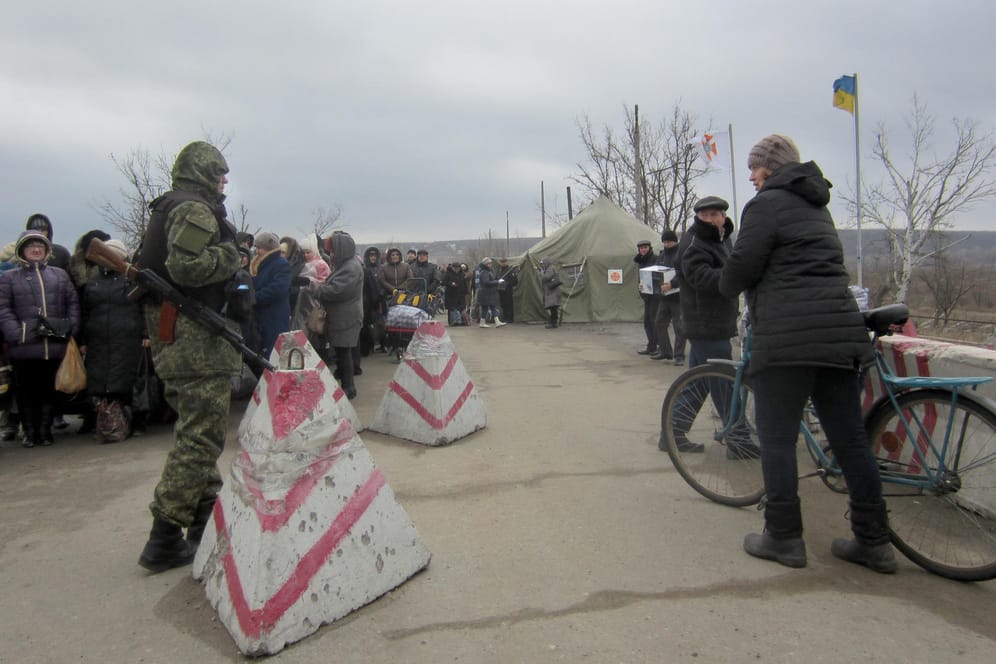 Eine Passantin spricht mit einem ukrainischen Grenzsoldaten an einem Kontrollpunkt zwischen Regierungs- und Rebellengebiet in der Ostukraine.