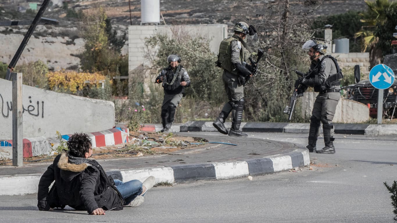 Ein palästinensischer Mann (l), der ein Messer in der Hand hält, liegt in Ramallah im Westjordanland auf dem Boden.