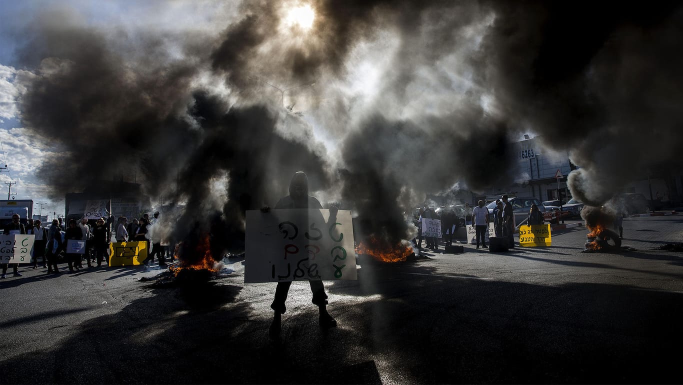Ein Demonstrant vor einem "Teva"-Werk in Ashdod: Brennende Reifen und Rauch.