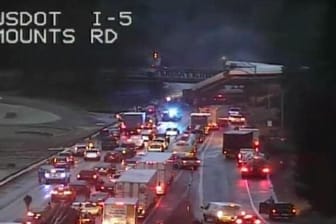 Eine Überwachungskamera zeigt Waggons des Zuges, die auf den Highway gestürzt sind.