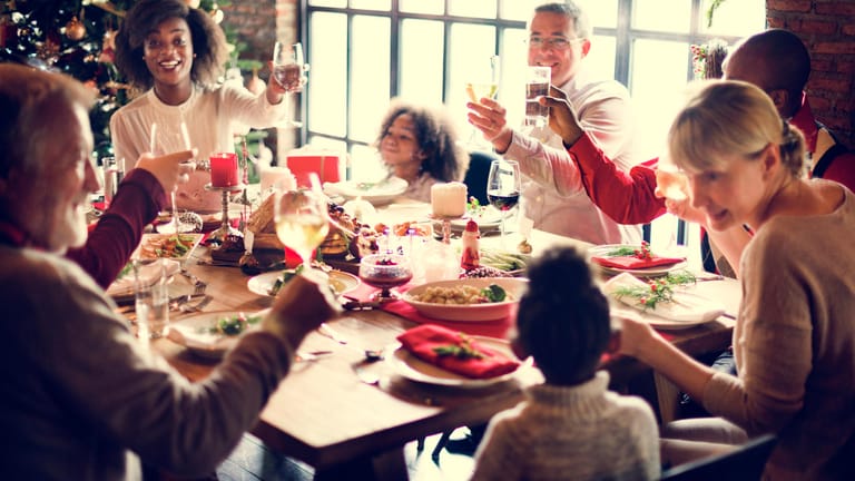 Eine Familie sitzt am gedeckten Tisch: An Weihnachten gehört für viele ein Glas Wein oder Bier dazu.