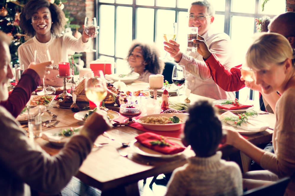 Eine Familie sitzt am gedeckten Tisch: An Weihnachten gehört für viele ein Glas Wein oder Bier dazu.