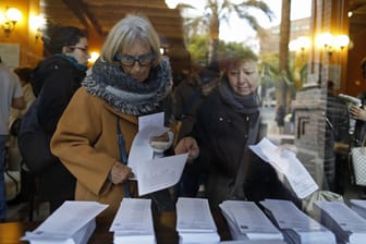 Wähler nehmen sich in Barcelona in einem Wahllokal einen Stimmzettel für die Neuwahl des Regionalparlaments in Katalonien.