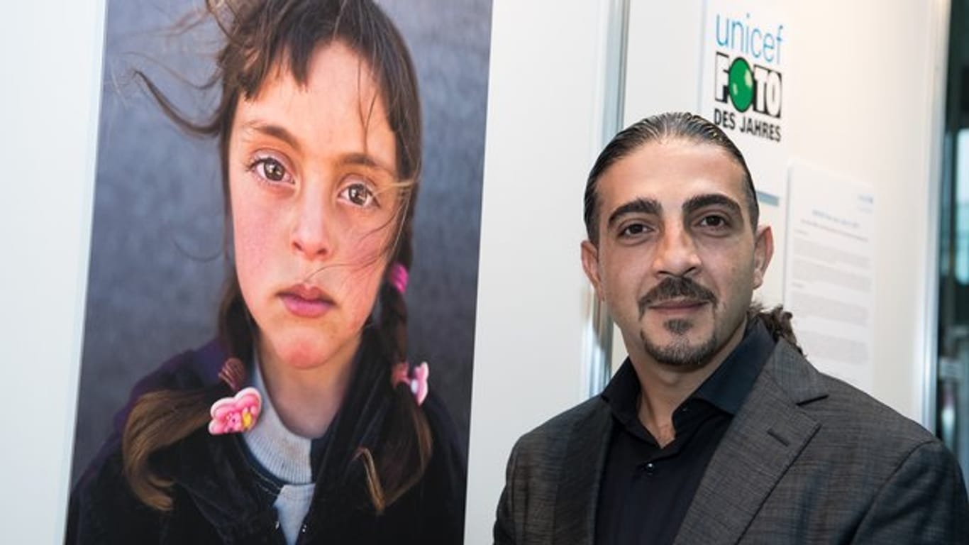 Preisträger Muhammed Muheisen steht bei der Preisverleihung des "Unicef-Foto des Jahres 2017" vor dem Siegerfoto in Berlin.