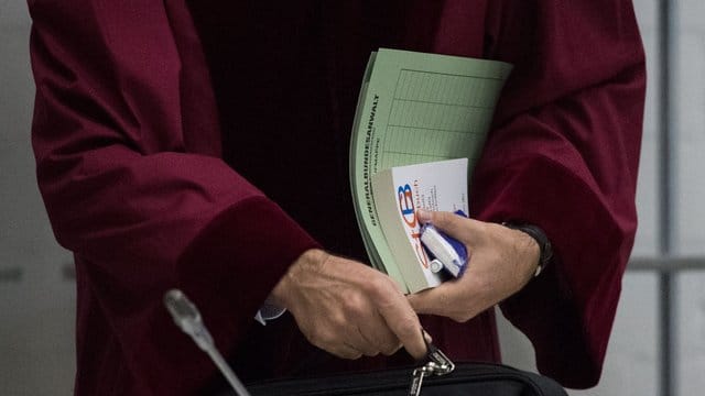Ein Staatsanwalt beim Bundesgerichtshof hält Prozessunterlagen und ein Strafgesetzbuch in der Hand. Ein Staatsanwalt beim Bundesgerichtshof hält Prozessunterlagen und ein Strafgesetzbuch in der Hand.